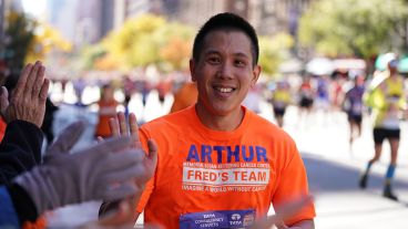 Arthur Li high-fives fans while running a race. 