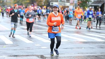 Abby Kaori smiles at the crowd on the sidelines while running a race.  