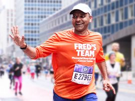 A Fred's Team runner smiling and waving while participating in the United Airlines NYC Half.