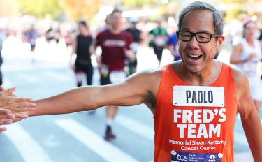 A Fred’s Team participant runs the TCS New York City Marathon in an orange Fred’s Team shirt. 