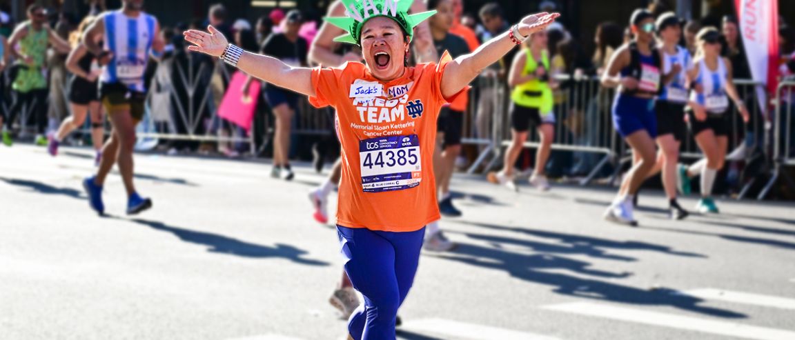 A Fred’s Team charity runner smiles and holds their arms out to the side while running the TCS New York City Marathon. 