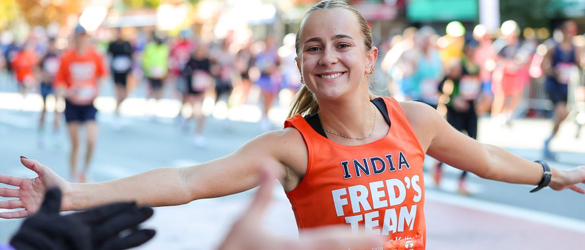 Runner in an orange jersey high-fives a spectator at a marathon event.