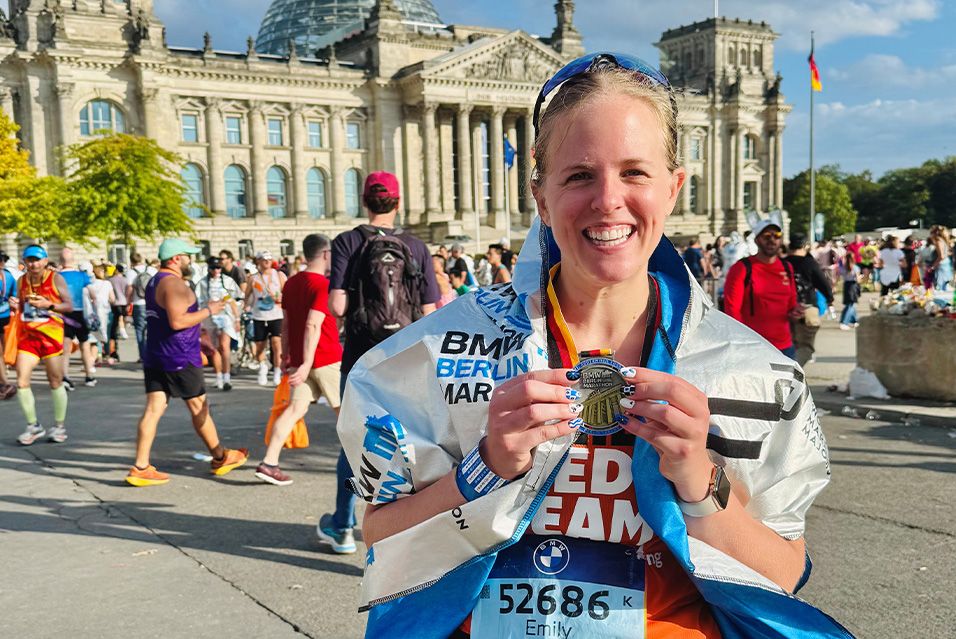 Fred’s Team charity runner Emily smiling and holding up her finisher’s medal from the 2025 BMW Berlin Marathon.