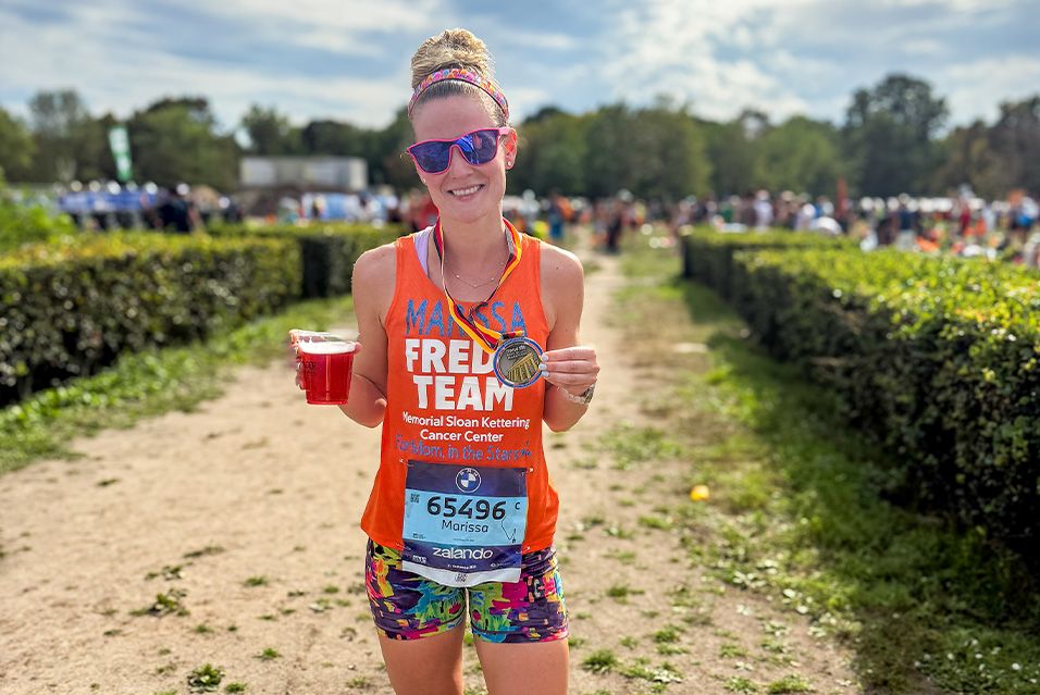Fred’s Team charity runner Marissa smiling and holding up her finisher’s medal from the 2025 BMW Berlin Marathon.